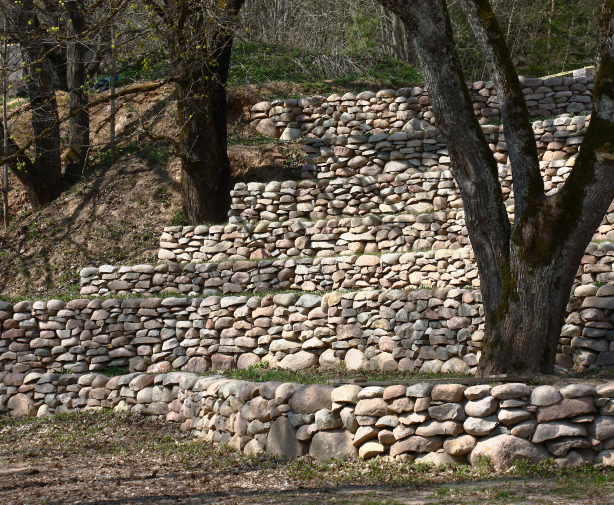 Large trees grow on the hill's slope, and numerous retaining walls are built out of natural stone
